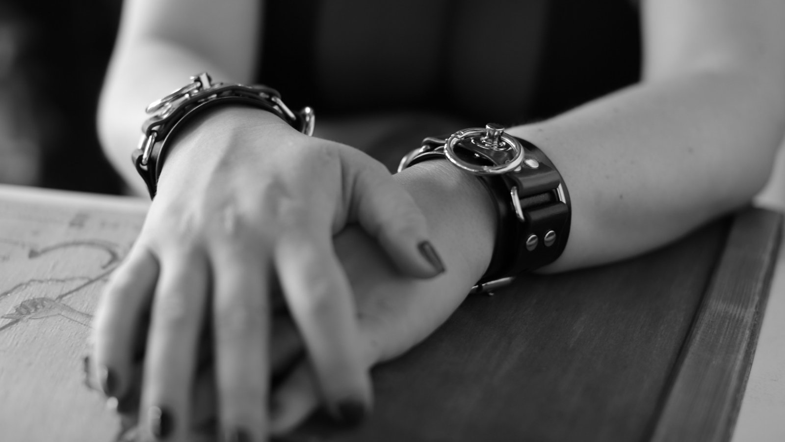 Hands with cuffs on a table; SFW